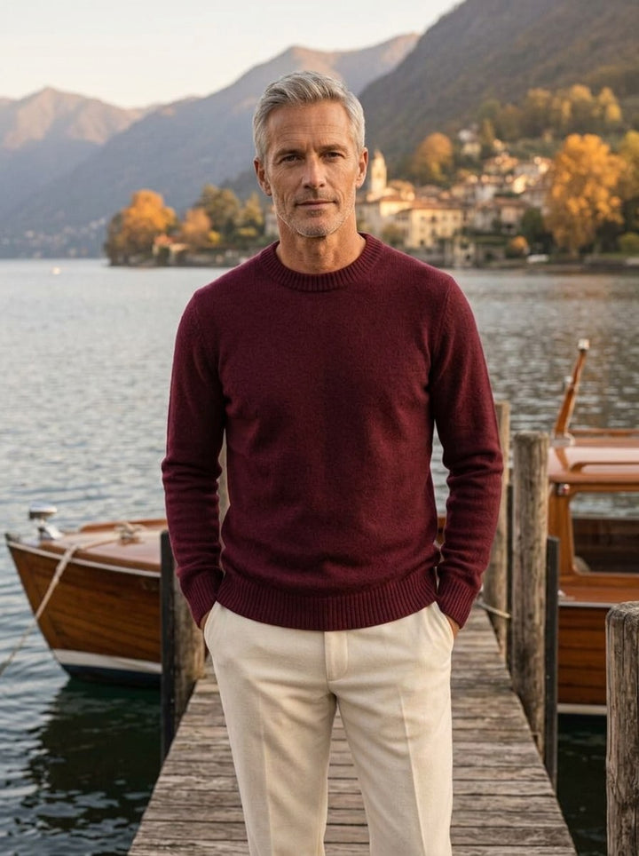 Man in a burgundy cashmere crewneck on a wooden lake jetty